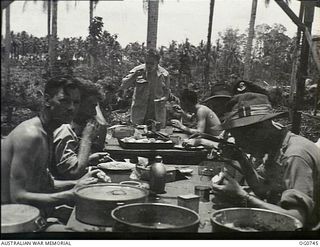 MOMOTE, LOS NEGROS ISLAND, ADMIRALTY ISLANDS. 1944-03-08. RAAF KITTYHAWK PILOTS HAVING THEIR LUNCH AT TABLES IN A PARTLY ERECTED CREW-ROOM NEAR THE AIRSTRIP. THEY ARE READY TO DROP THEIR FOOD AND ..