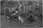 Women and children eat while dog watches