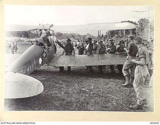 KIARIVU EMERGENCY LANDING GROUND, NEW GUINEA, 1945-08-13. THE ROYAL AUSTRALIAN AIR FORCE AIRCRAFT FLOWN BY FLYING OFFICER W.H.R. SMITH, BEING RECEIVED BY 2/7 INFANTRY BATTALION TROOPS AND NATIVES. ..