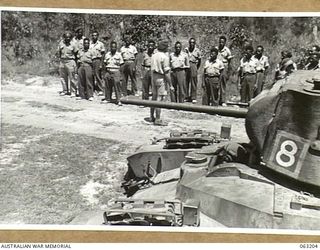 SOUTHPORT, QLD. 1944-01-18. NX48164 LIEUTENANT J. S. BEATTY OF THE FAR EAST LIAISON ORGANISATION, L.H.Q., LECTURING NEW GUINEA POLICE BOYS ON THE OPERATION OF A MATILDA TANK OF THE 4TH ARMOURED ..