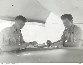 LAE BASE AREA, NEW GUINEA. 1944-12-04. NX20506 CORPORAL M. CHISHOLM (1) AND QX42351 CRAFTSMAN J. MCDOWALL (2) OF THE 2/77TH LIGHT AID DETACHMENT STUDYING THEIR ARMY EDUCATION SERVICE CORRESPONDENCE ..