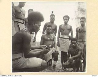 BISIATABU, NEW GUINEA. 1944-05-23. 140 CORPORAL DANGORO (2), INSTRUCTING NATIVE TROOPS OF THE PAPUAN INFANTRY BATTALION ON THE COMPONENT PARTS AND OPERATION OF A HAND GRENADE. IDENTIFIED PERSONNEL ..