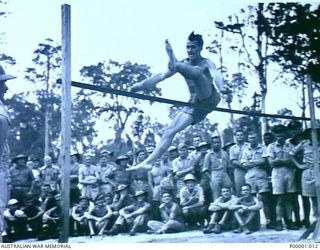 THE SOLOMON ISLANDS, 1945-01-12. A JUMPER WONDERS IF HE IS GOING TO MAKE IT HALF WAY THROUGH HIS HIGH JUMP AT A COMBINED ANZAC SPORTS MEETING AT BOUGAINVILLE ISLAND. (RNZAF OFFICIAL PHOTOGRAPH.)