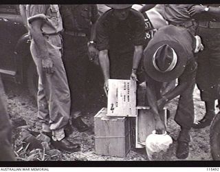 TOROKINA, BOUGAINVILLE. 1945-09-08. AN AUSTRALIAN ARMY OFFICER OPENING ONE OF TWO BOXES PRESENTED TO LIEUTENANT-GENERAL S. G. SAVIGE, GENERAL OFFICER COMMANDER 2 CORPS BY THE JAPANESE COMMANDER. ..