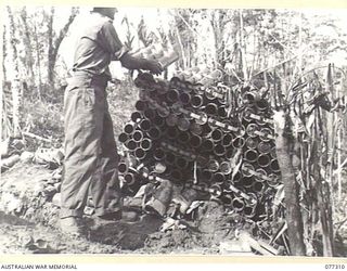 TOROKINA AREA, BOUGAINVILLE ISLAND. 1944-11-29. Q16519 PRIVATE T.A. FARROW, C COMPANY, 9TH INFANTRY BATTALION, STACKING EMPTY MORTAR BOMB CASES DURING THE ATTACK ON LITTLE GEORGE HILL