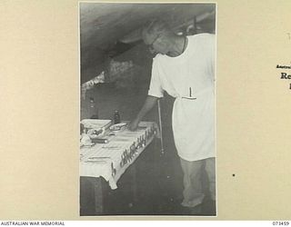 ALEXISHAFEN, NEW GUINEA, 1944-05-11. WX17085 CAPTAIN E.W. JONES, DENTAL OFFICER (1), EXAMINING INSTRUMENTS ON THE INSTRUMENT TABLE AT C SECTION, 2/5TH DENTAL UNIT