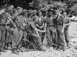 WIDE BAY, NEW BRITAIN. 1945-01-16. TROOPS OF "A" COMPANY, 14/32ND INFANTRY BATTALION ENJOYING A BIT OF FUN WITH A WRECKED JAPANESE BICYCLE AT KALAMPUN VILLAGE. IDENTIFIED PERSONNEL ARE:- V180385 ..