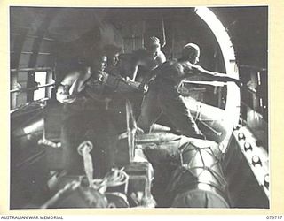 Members of  121 Supply Depot Platoon, Australian Army Service Corps hold a storepedo in readiness for a dropping sign from the pilot of the Douglas C47 Dakota transport aircraft. The line attached ..
