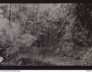 BULLDOG-WAU ROAD, NEW GUINEA, 1943-07-13. TROOPS OF HEADQUARTERS, ROYAL AUSTRALIAN ENGINEERS, 11TH AUSTRALIAN DIVISION, BENCHING A CLIFF FACE ABOVE THE ELOA RIVER, AT THE 19 MILE POINT. MEN WORKING ..