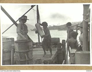 KWIARA, CHINA STRAITS, 1943-07-03. NATIVE BOYS UNLOADING SUPPLIES FROM THE AK-60