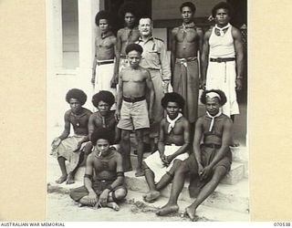 PORT MORESBY, PAPUA, 1944-02. P382 CHAPLAIN M. MCENROE, M.S.C., CHAPLAIN OF THE AUSTRALIAN PAPUA ADMINISTRATIVE UNIT, OUTSIDE THE ROMAN CATHOLIC CHURCH OF "OUR LADY OF THE ROSARY", WITH NATIVE ..