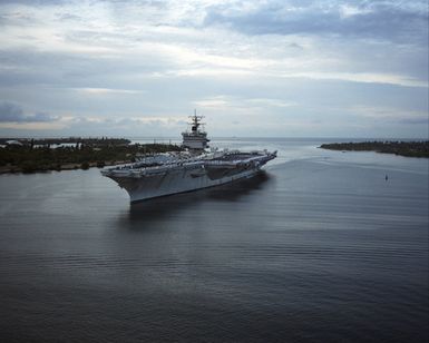 Aerial port bow view of the nuclear-powered aircraft carrier USS ENTERPRISE (CVN 65) as it enters Pearl Harbor. Members of the crew man the rail