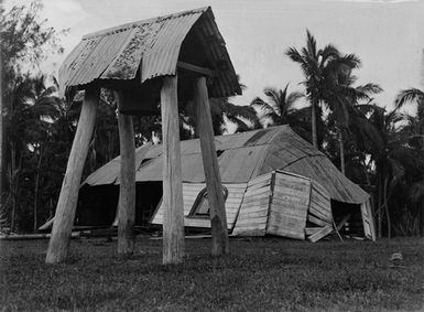 [Bell tower and damaged building with corrugated iron roofing]