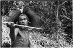 Gardening: man wearing feather headdress holds digging stick like a spear