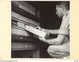 CAPE WOM, NEW GUINEA. 1945-09-27. SERGEANT R.J. MCCOY, 110 BRIGADE ORDNANCE FIELD PARK, ATTENDING TO THE ISSUE OF TECHNICAL STORES