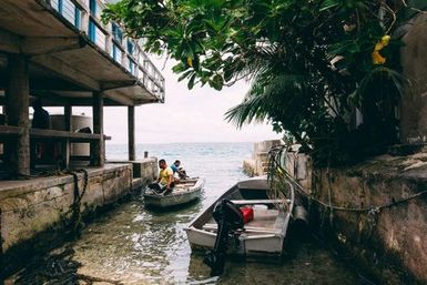 Two men in boat in dockway, Fakaofo, Tokelau