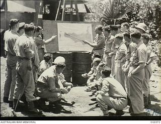 KIRIWINA, TROBRIAND ISLANDS, PAPUA. C. 1943-12. AIRCREW OF NO. 22 (BOSTON) SQUADRON RAAF BEING BRIEFED ON THE CAPE GLOUCESTER LANDING FROM A BRIEFING OFFICER