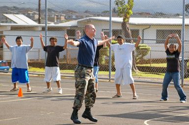 US Navy (USN) Electrician's Mate Second Class (EM2) Jason Switzer, assigned to Mobile Diving Salvage Unit 1 (MDSU-1) leads children through warm-up exercises during a Community Relations (COMREL) visit at Waipahu Elementary School, Hawaii (HI)