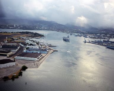 An aerial port quarter view of the nuclear-powered aircraft carrier USS ENTERPRISE (CVN 65) as it enters Pearl Harbor. Members of the crew man the rail