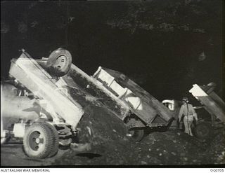 NADZAB, NEW GUINEA. C. 1944-02. TRUCKS OF NO. 62 MOBILE WORKS SQUADRON RAAF DUMPING GRAVEL ON NADZAB AIRSTRIP AT NIGHT. THEY WORK UNDER FLOODLIGHTS