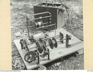 KILIGIA, NEW GUINEA. 1944-04-08. AN IMPROVISED COIL WINDER MADE BY PERSONNEL OF "M" SECTION, 5TH DIVISION SIGNALS AT HEADQUARTERS 5TH DIVISION. POWER FROM A 6 VOLT BATTERY DRIVES A MOTOR CYCLE ..