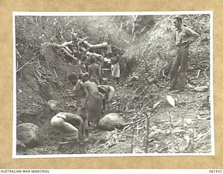 DUMPU, NEW GUINEA. 1943-12-06. VX38769 CORPORAL W. W. BAIRLEY OF THE 18TH AUSTRALIAN ANTI-MALARIAL CONTROL UNIT SUPERVISING A TEAM OF NATIVE BOYS WHO ARE CLEARING A CREEK BED OF ALL RUBBISH AND ..