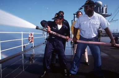 Boiler Mate Third Class (BT3) Turner (left), and SEAMAN (SN) Thumate receive some hands on experience in handling a fire hose during damage control training aboard the amphibious command ship USS BLUE RIDGE (LCC-191) while the ship is steaming off the coast of Guam during exercise Tempo Brave '94