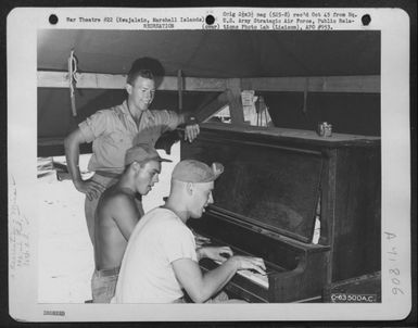 A Gi Grins Happily As Two Of His Buddies Beat Out A Tune On The Piano Which Was Brought From San Francisco For Special Services, 392Nd Bomb Squadron, 30Th Bomb Group. Kajalein, Marshall Islands. 23 April 1944. (U.S. Air Force Number C63500AC)