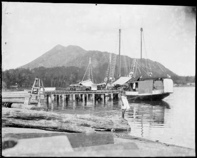 Mother Mountain, with moored ships and a man standing on a log in the foreground, Rabaul Harbour, New Guinea, ca. 1929, 2 / Sarah Chinnery