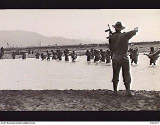 UMI RIVER, NEW GUINEA. 1943-09-29. A DETACHMENT OF THE PAPUAN INFANTRY BATTALION AND NATIVE CARRIERS CROSSING THE RIVER WITH THE AID OF A HAND ROPE