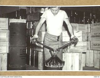 KENSINGTON, VIC. 1943-10-23. AN EMPLOYEE OF MESSRS. KIMPTON & SONS, FLOUR MILLERS, USING A CLAMPING TOOL TO SEAL A DRUM OF FLOUR FOR DESPATCH TO THE TROOPS IN NEW GUINEA