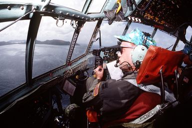 The mission commander aboard a 374th Airlift Wing C-130 Hercules aircraft examines the drop zone as he prepares to deliver boxes of gifts to islanders of the Federated States of Micronesia. Flown by crews from the 345th and the 21st Airlift Squadrons, the C-130 is participating in Christmas Drop '92, the 40th anniversary of the humanitarian effort. Every Christmas since 1952, food, clothing, tools and toys donated by residents of Guam have been delivered by air to 40 Micronesian islands
