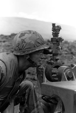 Colonel Radcliff, left, Commanding Officer of the 3rd Marine Regiment, 1ST Marine Brigade, looks through the sight of an M101 105 mm howitzer during Operation ZULU WARRIOR at the Pakalula Training Area