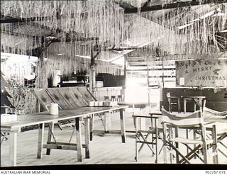 Madang, New Guinea, 1945-12-25. Interior of the Officers' Mess at Headquarters, RAAF Northern Command (NORCOM), decorated for Christmas. Streamers improvised from some sort of local grass hang down ..