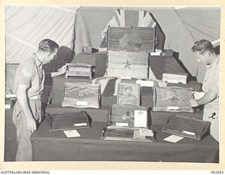 LAE AREA, NEW GUINEA. 1945-06-03. CORPORAL D.B. HACKETT (1) AND SERGEANT H.J. HOKIN (2), INSTRUCTORS AT 112 CONVALESCENT DEPOT, ARRANGING PRIZE WINNING EXAMPLES OF POLISHED WOODWORK AT AN ..