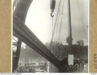 LAE, NEW GUINEA. 1944-06-14/02. A HEAVY CRANE OF THE UNITED STATES ARMY BEING USED TO UNLOAD STEEL RAILS FROM THE AK94, A VESSEL OF THE 12TH WATER TRANSPORT OPERATING COMPANY. THESE RAILS ARE TO BE ..