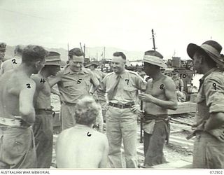 MILNE BAY, NEW GUINEA. 1944-04-21. THE HONOURABLE E.J. WARD, MINISTER FOR EXTERNAL TERRITORIES IN THE AUSTRALIAN GOVERNMENT (5), SPEAKING WITH ENGINEERS ENGAGED IN THE CONSTRUCTION OF A NAVAL ..