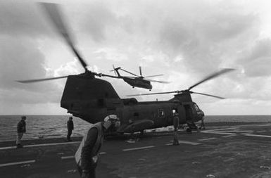 A right side view of a CH-46 Sea Knight helicopter on the flight deck of the amphibious assault ship USS GUAM (LPH 9), during operations off the coast of Beirut, Lebanon. Behind the Sea Knight is a CH-53 Sea Stallion helicopter