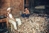 American Samoa, men sitting among pile of coconut shells