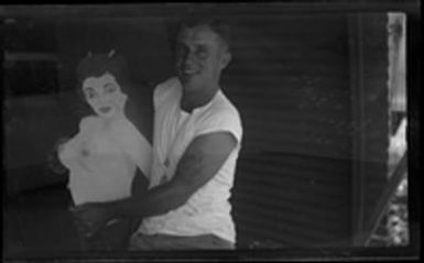 [Serviceman posing with cutout of topless woman]