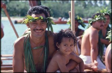 Man wearing wreath and necklaces, and child