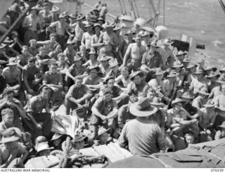 AT SEA. 1944-10-07. SX2915 LIEUTENANT COLONEL O.C. ISAACHSEN, COMMANDING OFFICER 36TH INFANTRY BATTALION LECTURING HIS TROOPS ON THE TERRAIN OF NEW IRELAND WHILE EN ROUTE TO THE ISLAND ABOARD THE ..