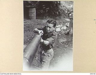 TOROKINA, BOUGAINVILLE, 1945-08-14. TROOPER N.E. MANNELL CLEANING THE BORE OF A 75MM GUN ON AN M24 LIGHT TANK DURING ACTIVITIES OF THE BRITISH WAR OFFICE TRIALS TEAM (TANKS)