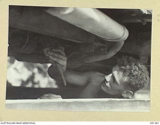 TOROKINA, BOUGAINVILLE. 1945-04-28. CRAFTSMAN C. MUKLING, TRANSPORT AND LIGHT AID DETACHMENT SECTION, ATTACHED HEADQUARTERS 2 CORPS, AT WORK ON THE RAMP CLEANING THE UNDERNEATH OF A JEEP