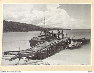 MUSCHU ISLAND, NEW GUINEA. 1945-10-10. PIER AT THE BEACHHEAD ON MUSCHU ISLAND WHICH WAS CONSTRUCTED BY JAPANESE TROOPS TO RECEIVE AUSTRALIAN FAST SUPPLY BOATS. MAJOR E.S. OWENS, ASSISTANT ADJUTANT ..