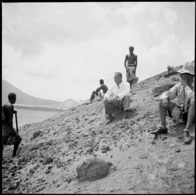 Two Europeans and three other men on a stony slope with mountains in the  background, Rabaul, New Guinea, 1937 / Sarah Chinnery