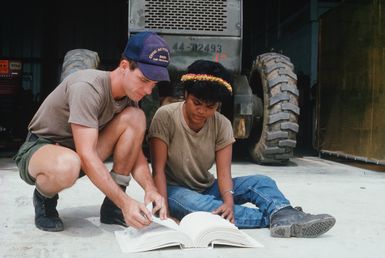 Beverly Imeong, a mechanic trainee, reviews a technical manual with Construction Mechanic 2nd Class Kevin Griffitts. Griffitts and other United States Navy construction battalion members are part of a Civic Action Team deployed to the island of Yap to offer vocational training and to aid villagers with construction projects