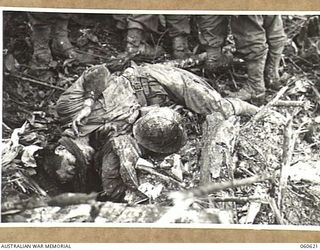 SATTELBERG AREA, NEW GUINEA. 1943-11-18. THE BODY OF A DEAD JAPANESE SOLDIER IN FRONT OF HIS DUGOUT. TAKEN DURING THE ASSAULT ON SATTELBERG