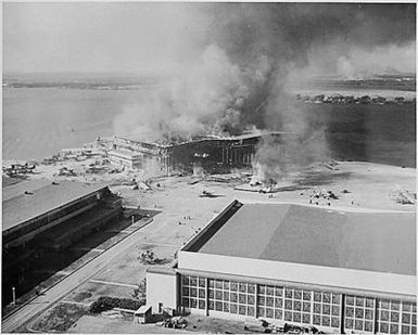 Naval photograph documenting the Japanese attack on Pearl Harbor, Hawaii which initiated US participation in World War II. Navy's caption: Burning barracks at Ford Island, Pearl Harbor, Hawaii, after being attacked by Japanese aircraft on Dec.7, 1941.