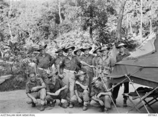 RABAUL, NEW BRITAIN. 1945-09-23. A GROUP OF GUARDS FROM A SECTION OF 37/52 INFANTRY BATTALION BESIDE THEIR TEND IN WHICH THEY HAVE INSTALLED AN ELECTRIC SYSTEM CONSTRUCTED FROM JAPANESE READING ..